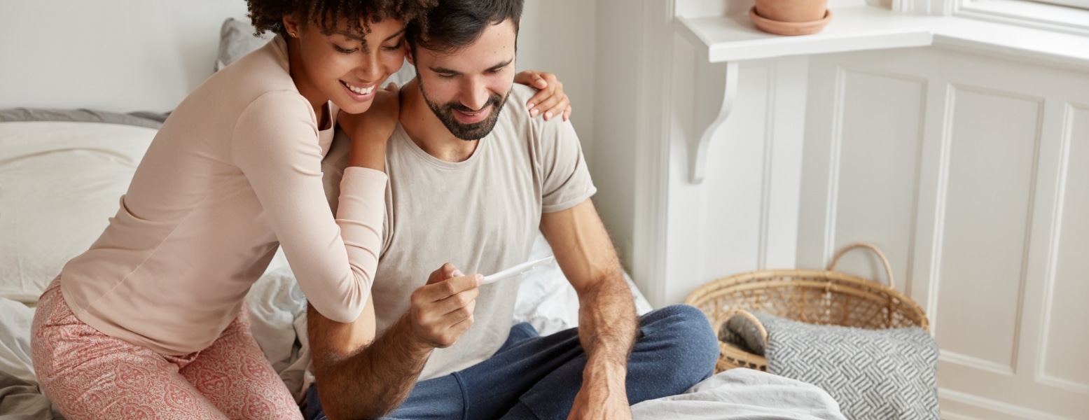 cheerful-dark-skinned-woman-embraces-her-husband-shows-positive-result-test-rejoice-they-will-become-parents-soon